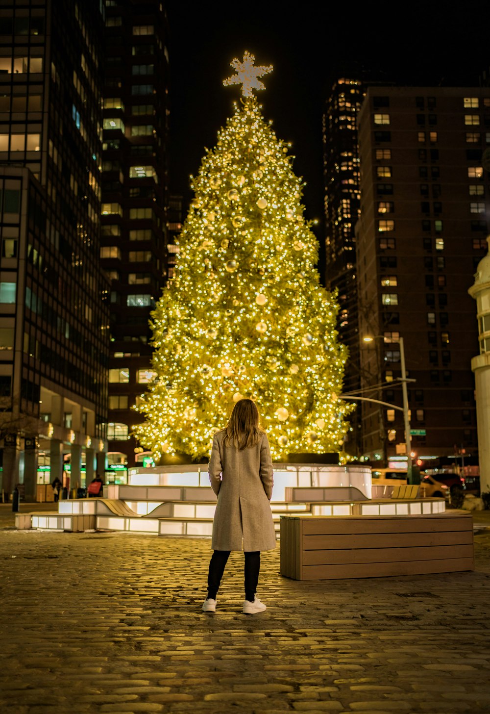 Una donna in piedi davanti a un grande albero di Natale