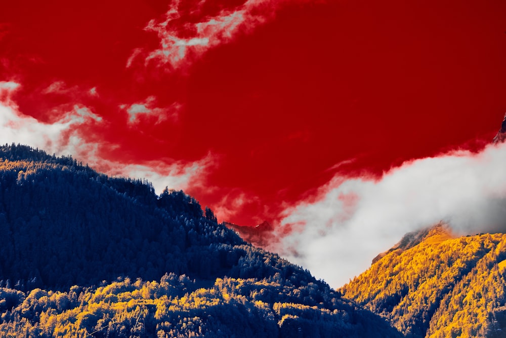 a red sky over a mountain covered in trees