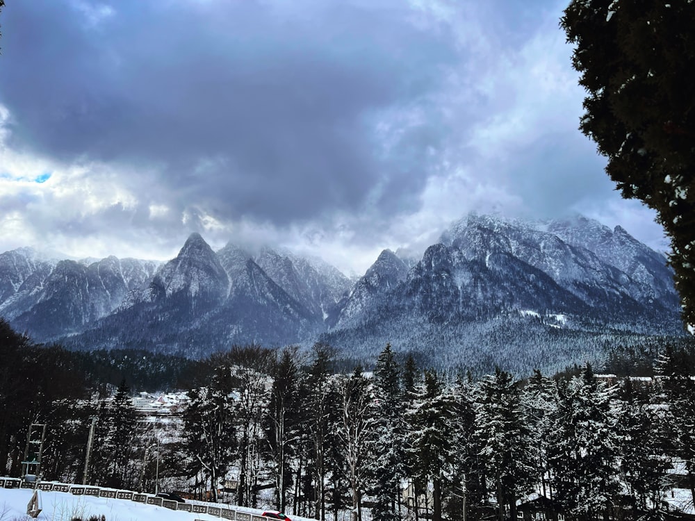 a snow covered mountain range under a cloudy sky