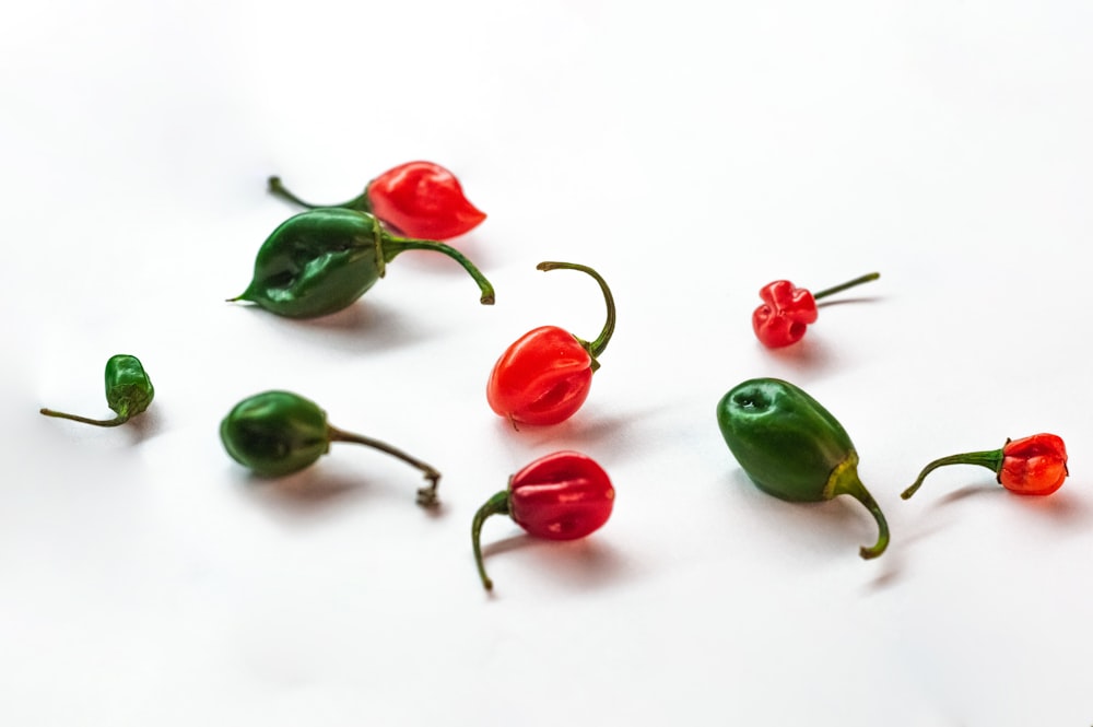 a group of red and green peppers on a white surface