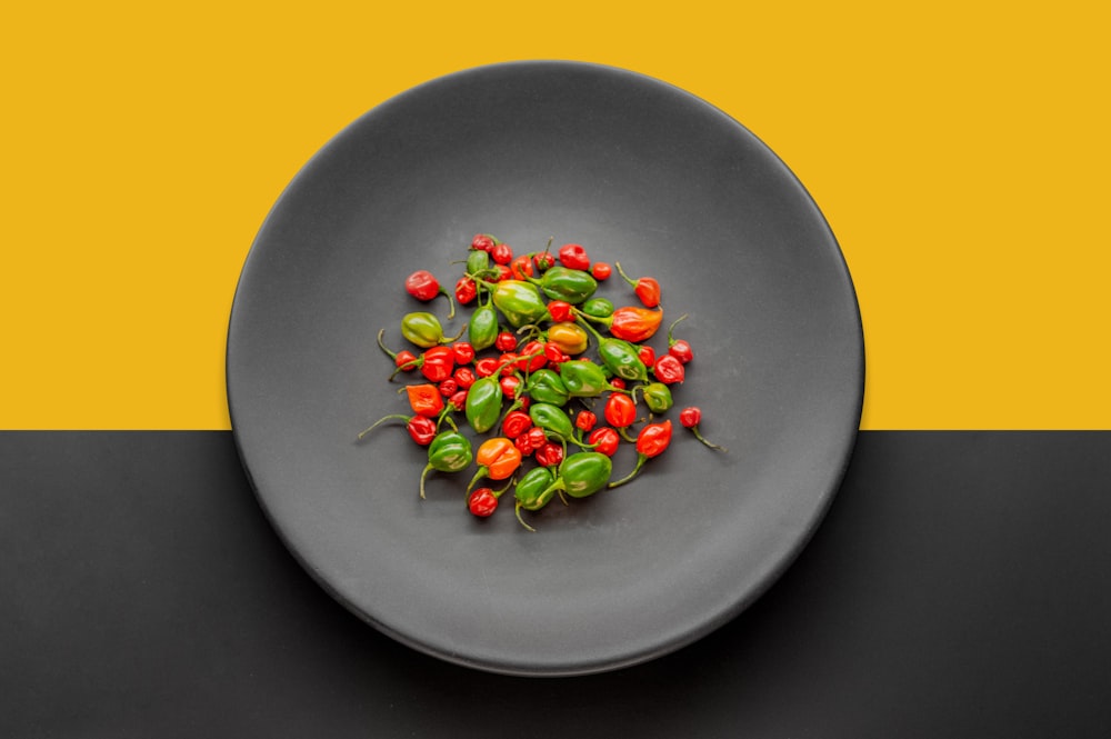 a black plate topped with green and red peppers