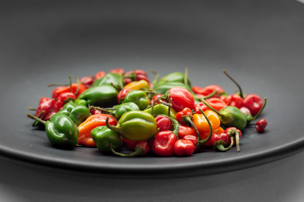 a black plate topped with lots of green and red peppers