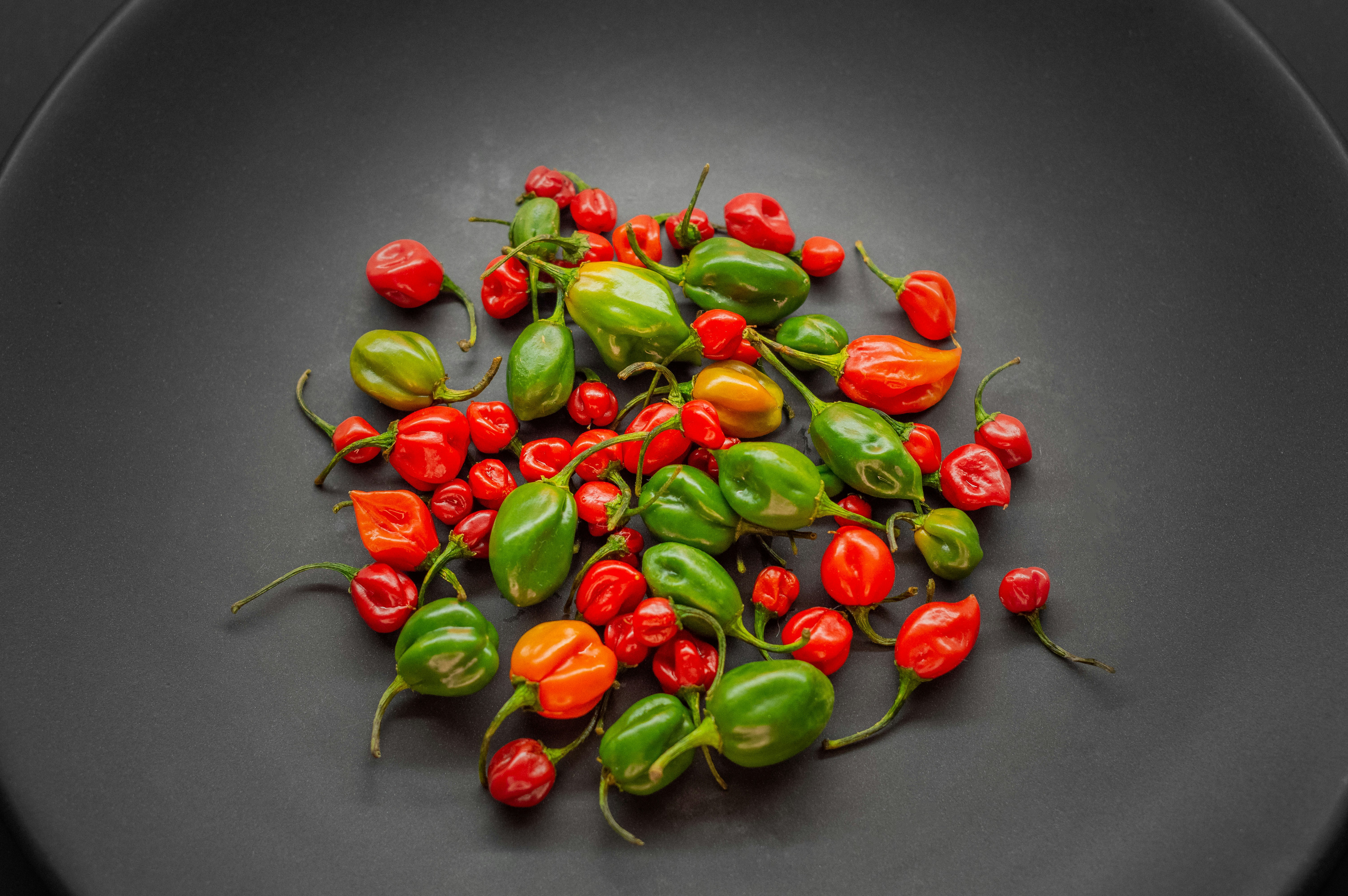 a black plate topped with lots of red and green peppers