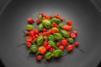 a black plate topped with lots of red and green peppers