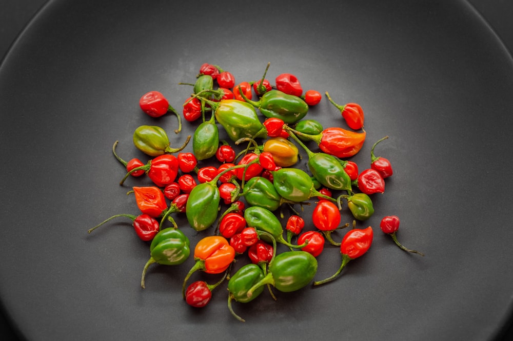 a black plate topped with lots of red and green peppers