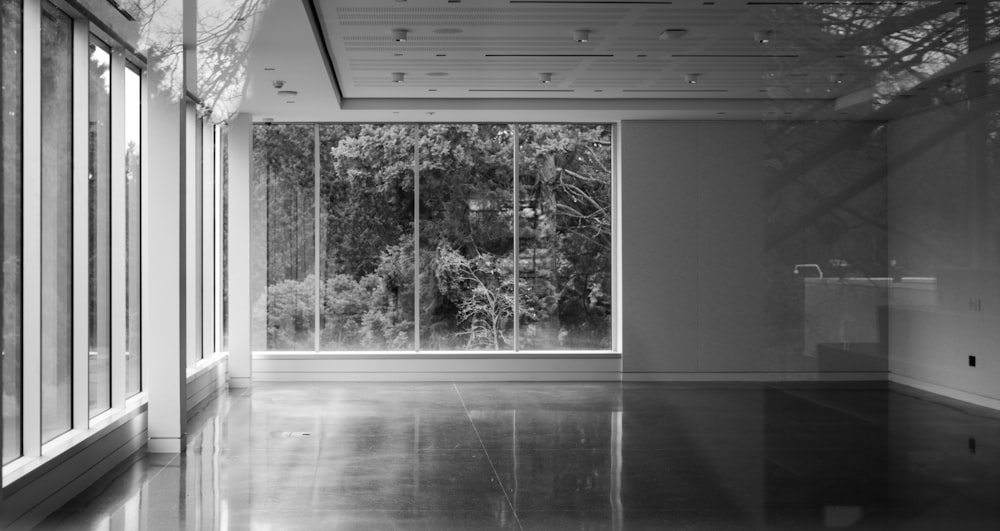 une chambre vide avec de grandes fenêtres et une vue sur les arbres