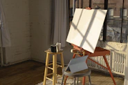 A cozy studio filled with unique artworks and natural light streaming through large windows.