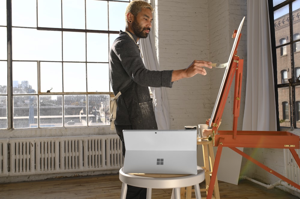 a man standing in front of a easel painting a picture