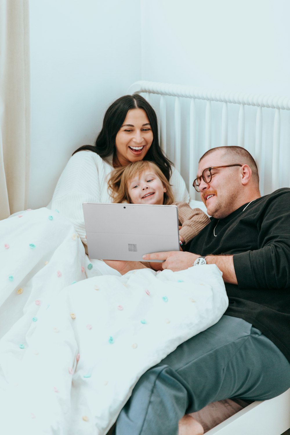 a man and a woman sitting on a bed with a laptop