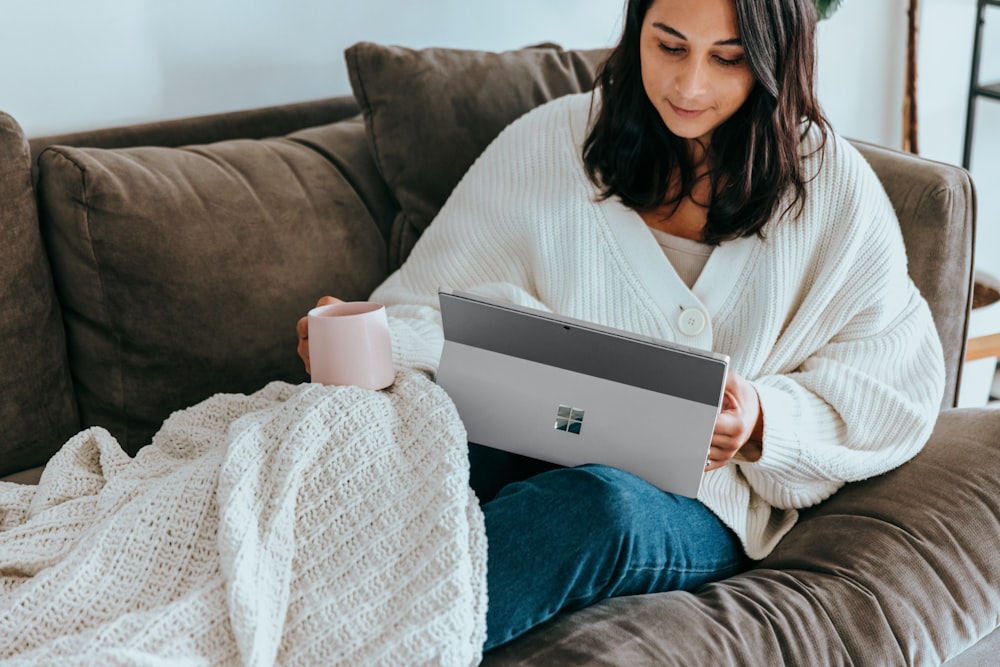 a woman sitting on a couch holding a laptop