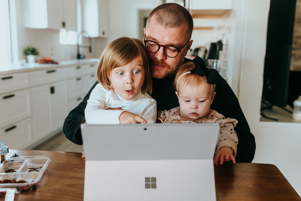 Un uomo e due bambini che guardano un computer portatile