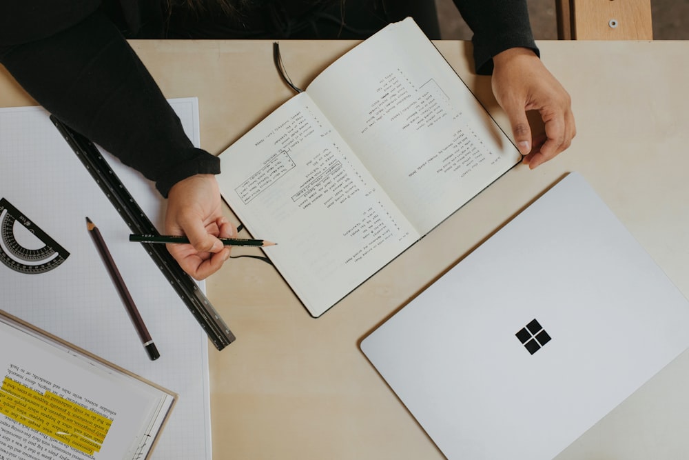 eine Person, die einen Stift hält und auf ein Buch schreibt