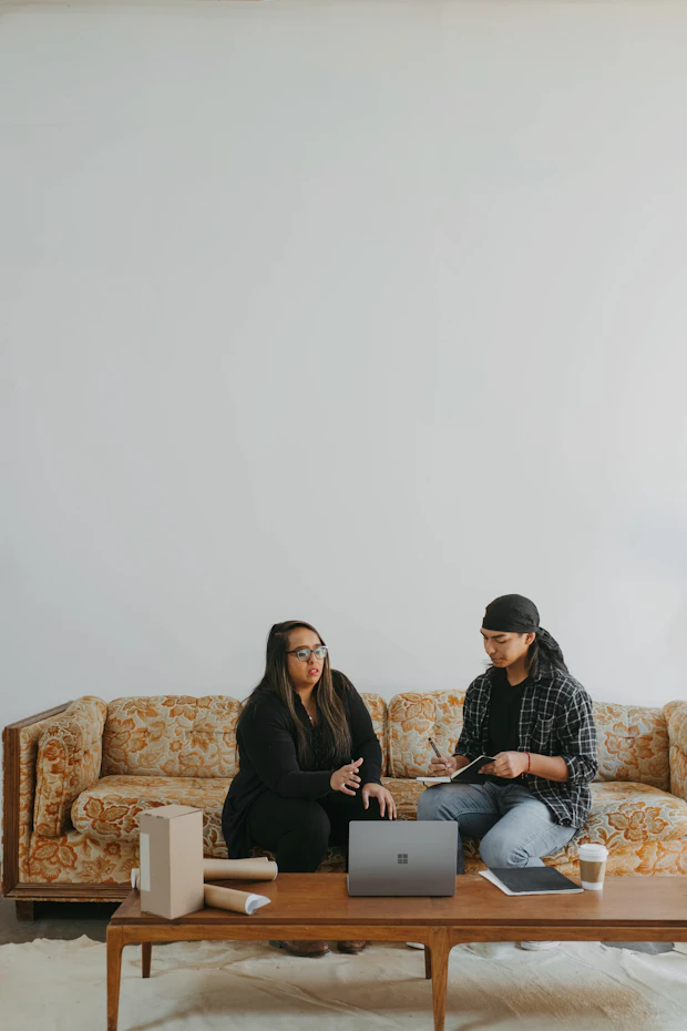 Duas pessoas no sofá da sala olhando juntas para um notebook