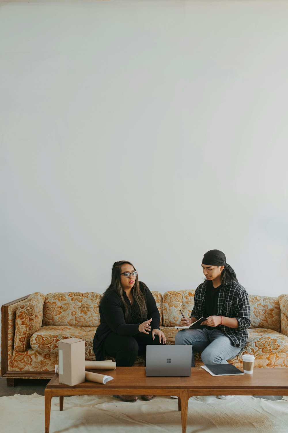 two people sitting on a couch looking at a laptop