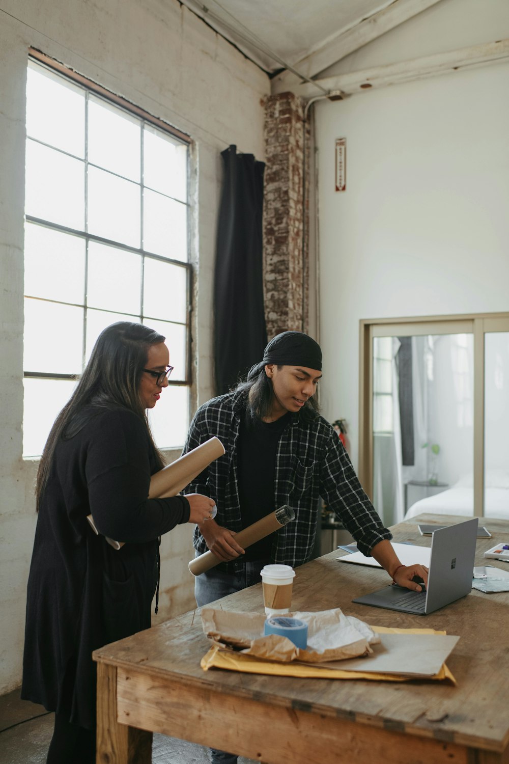 a couple of people standing around a wooden table