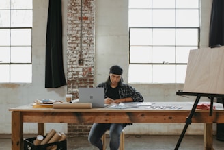 a man sitting at a table working on a laptop