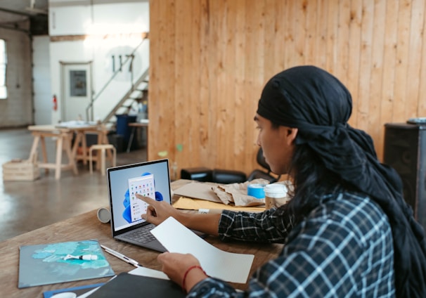 a woman sitting at a table using a laptop computer