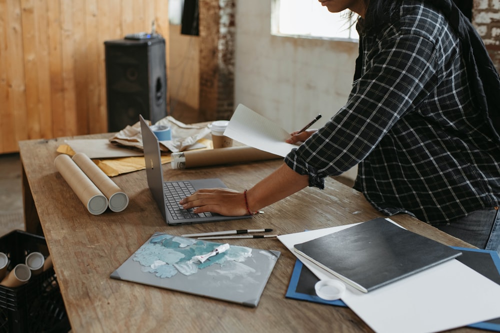 Una mujer sentada en una mesa trabajando en una computadora portátil