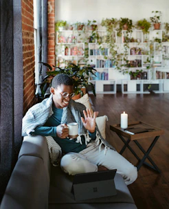 A cozy scene showing a person gently wrapping a soft heating pad around their lower back while sitting comfortably on a couch.