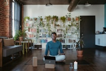 a man sitting on a yoga mat with a laptop in front of him