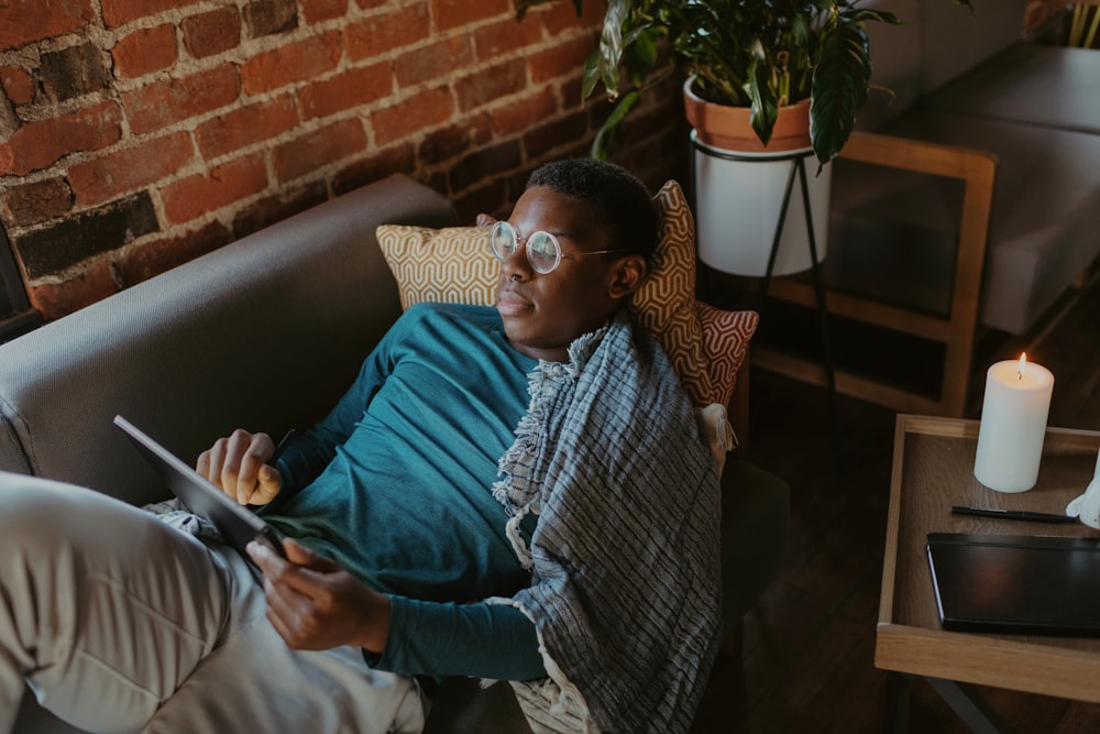 a man sitting on a couch holding a tablet