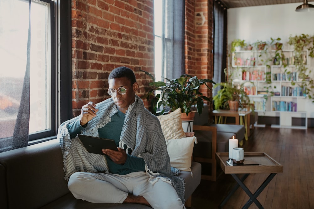 Une femme assise sur un canapé regardant une tablette