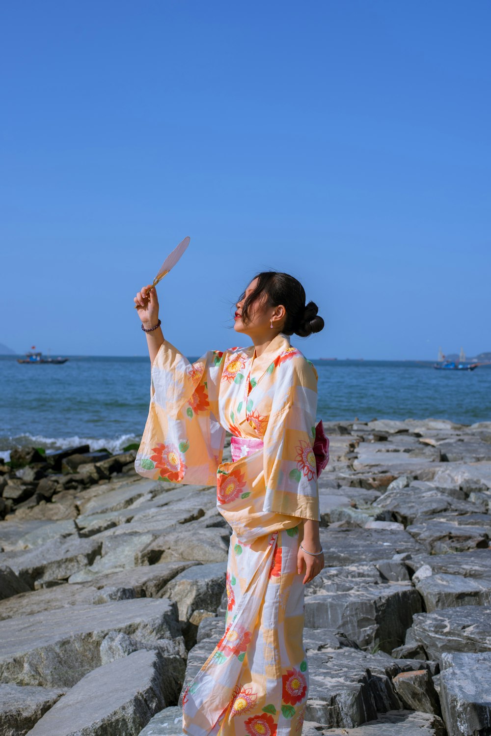 a woman in a kimono standing on a rocky beach