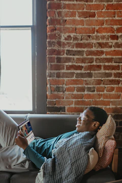 A person comfortably using an android tablet in a cozy living room.