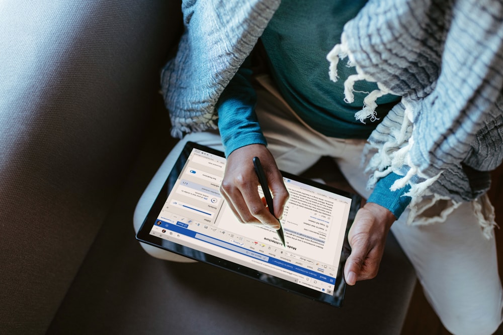 a person sitting down writing on a tablet