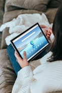 a woman sitting on a couch holding a tablet