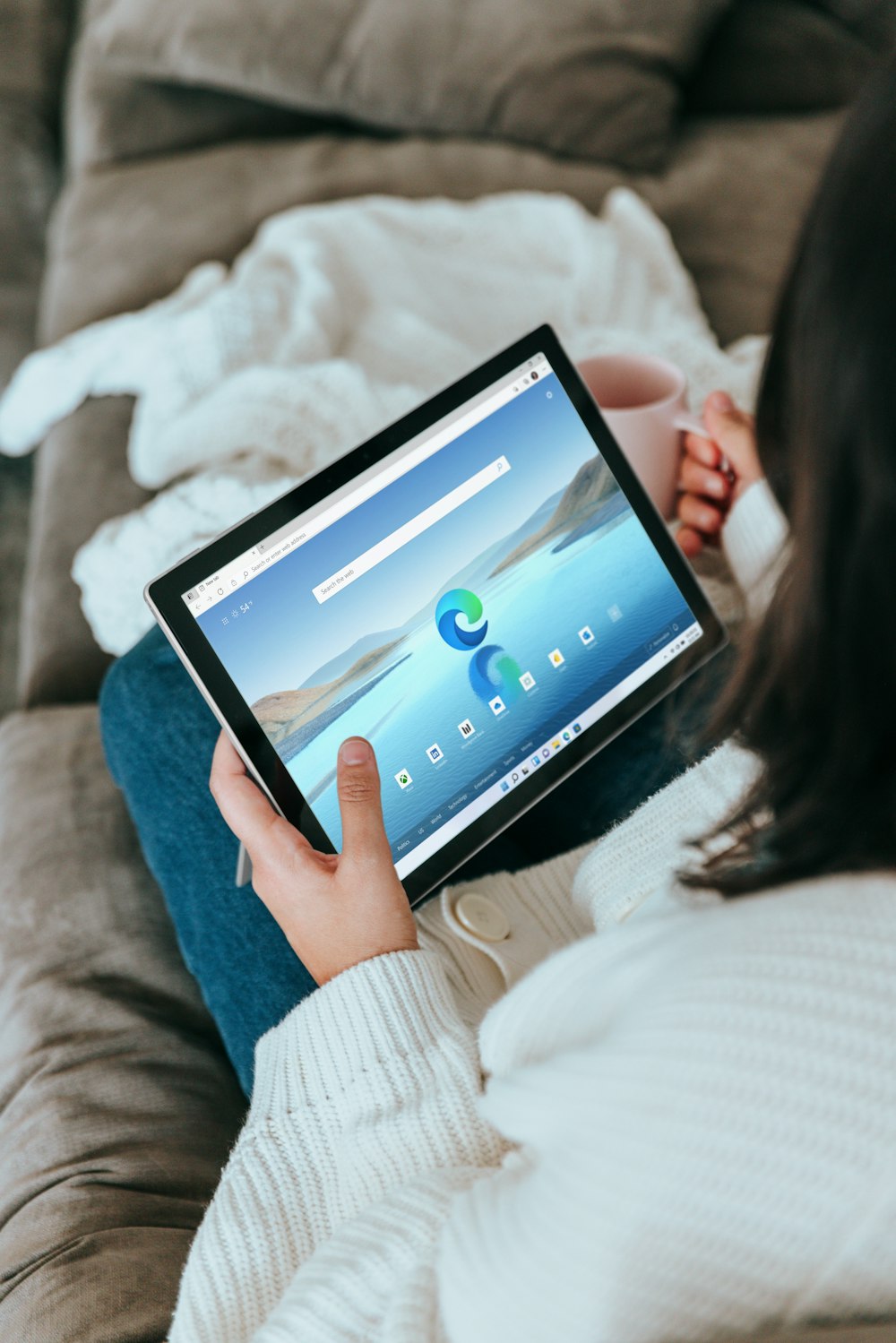 a woman sitting on a couch holding a tablet