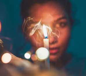 a woman holding a lit candle in front of her face