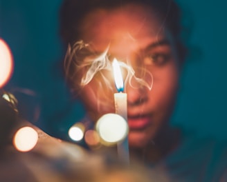 a woman holding a lit candle in front of her face