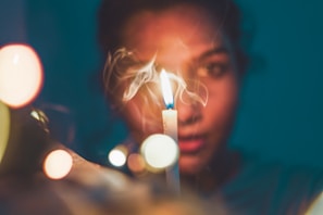 a woman holding a lit candle in front of her face