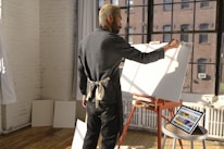 A local artisan painting intricate patterns inside a sunlit studio filled with handcrafted goods.