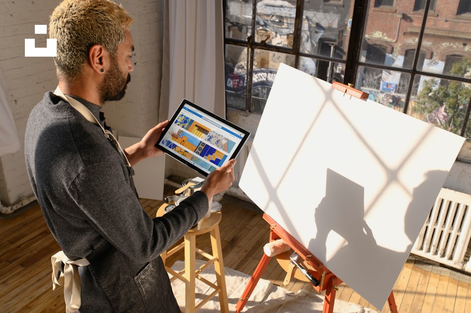 A man standing in front of a easel holding a tablet photo – Free ...