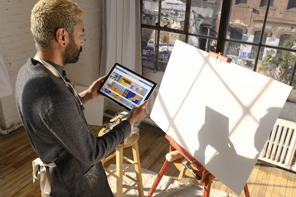 a man standing in front of a easel holding a tablet