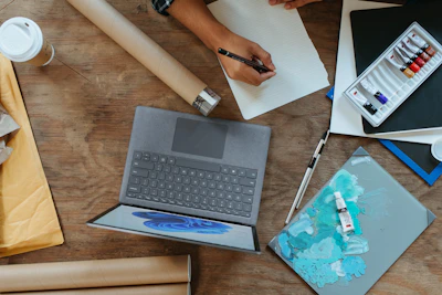 A vibrant illustration of a young writer typing passionately on a laptop surrounded by floating pages and ink splashes.