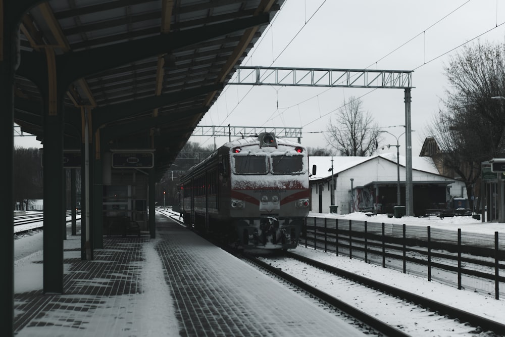 a train traveling down train tracks next to a snow covered platform