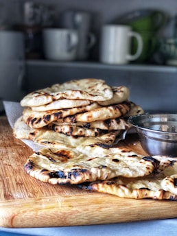 Freshly baked Arabic breads stacked beside colorful dishes ready to be served.