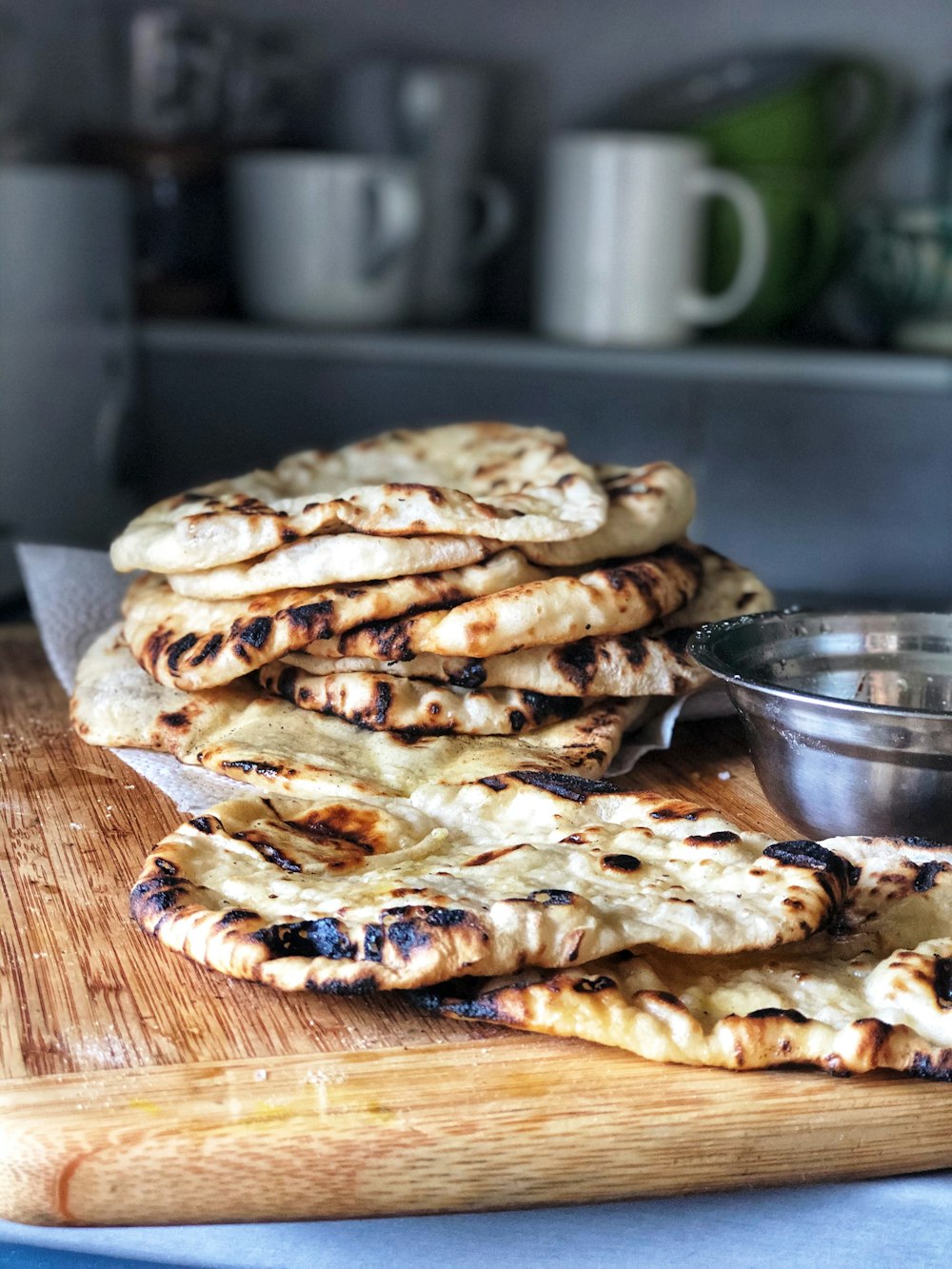 a pile of pita bread sitting on top of a wooden cutting board