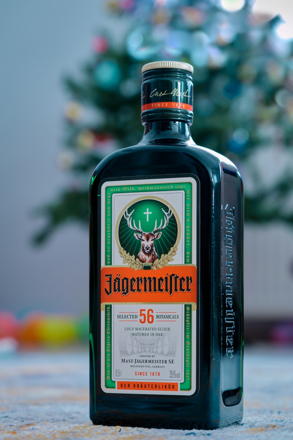 Una bottiglia di liquore seduta su un tavolo accanto a un albero di Natale