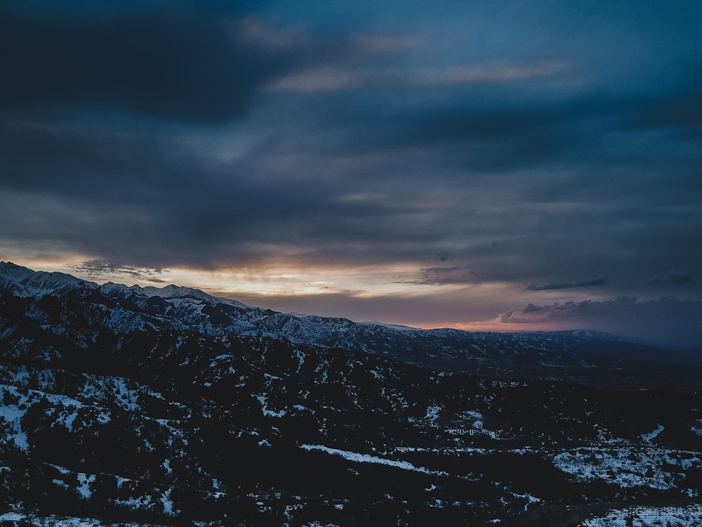 the sun is setting over a snowy mountain range