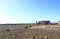 Rustic desert adobe home under a vast blue sky.
