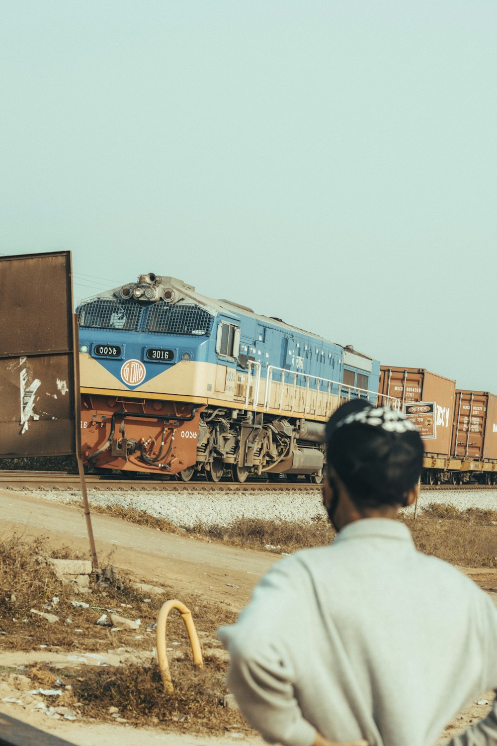 a man looking at a train on the tracks