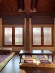 A cozy deluxe room featuring traditional Indian furnishings and a window overlooking the temple.