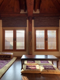 A cozy deluxe room featuring traditional Indian furnishings and a window overlooking the temple.