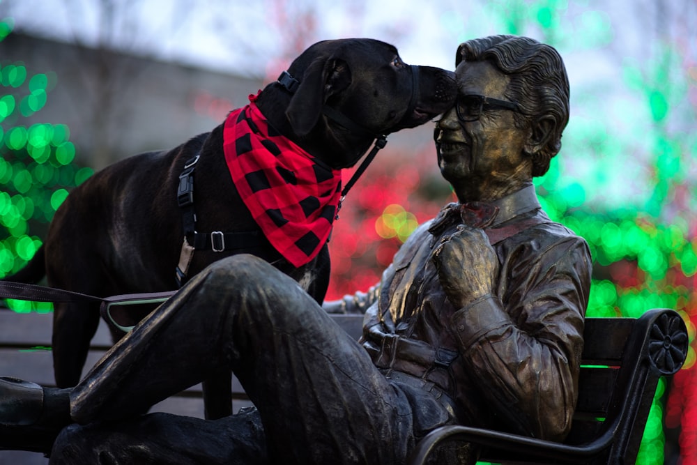 a statue of a man sitting on a bench next to a dog