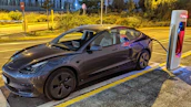 Electric car plugged into a sleek charger with a minimalist home background.