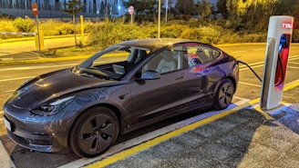 A sleek electric car plugged into a modern charging station at sunset.